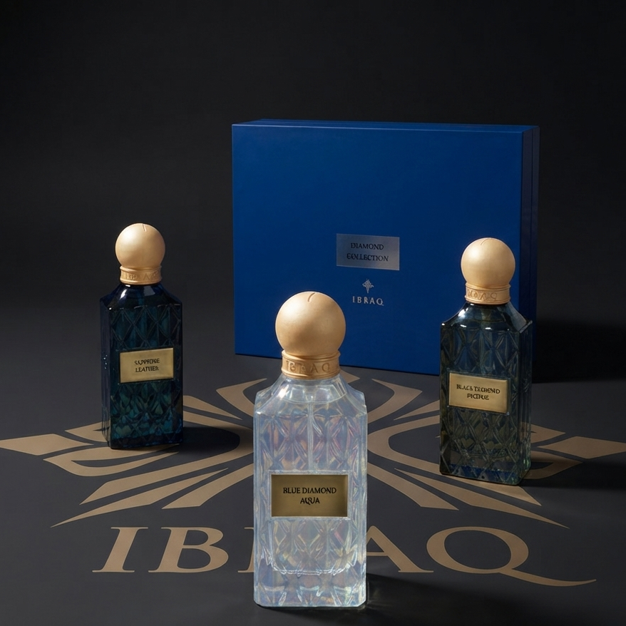 Three faceted glass perfume bottles with round wooden caps are arranged in front of a blue presentation box on a dark surface. The center bottle is clear and labeled 'Blue Diamond Noor', while the two side bottles are deep blue and labeled 'Saffron Gold' and 'Blue Diamond Noor'.