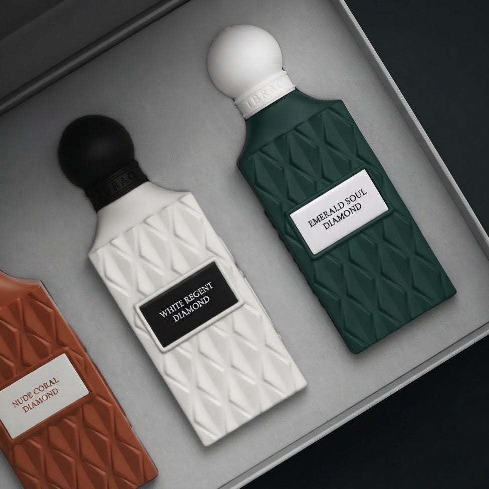 Three perfume bottles displayed in a gray presentation box, including White Mossy Diamond, Emerald Soul Diamond, and Norwegian Diamond, with textured bottle designs and white labels. SHE GLOW 