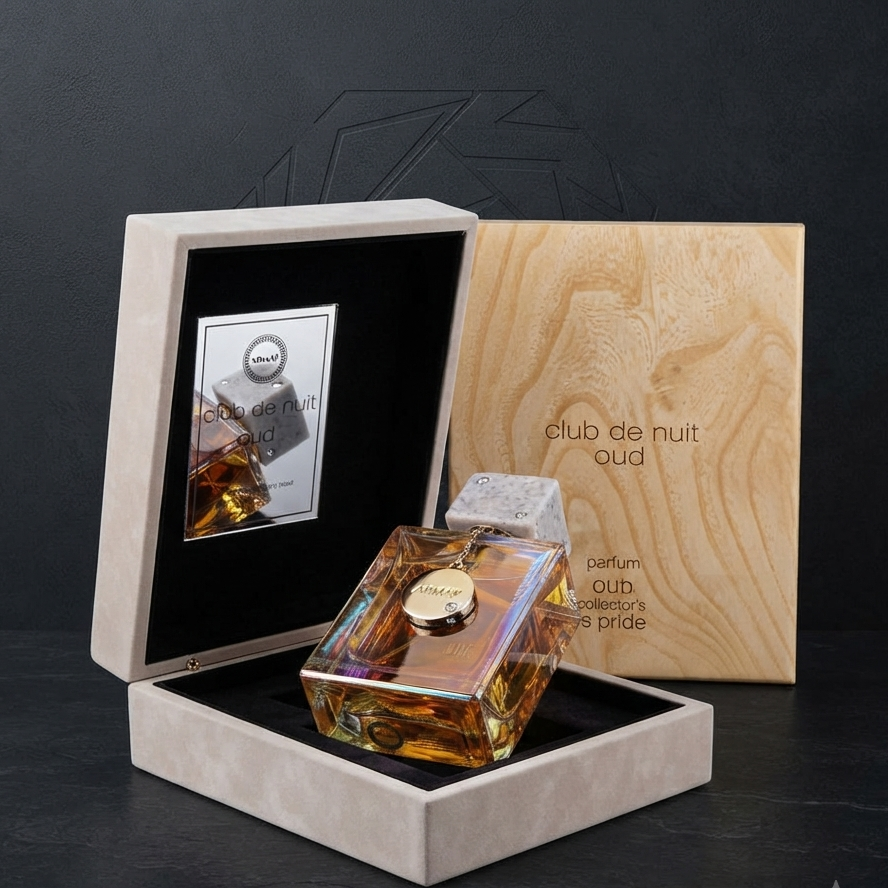 A luxury perfume bottle with an iridescent amber liquid and a clear cap, presented inside an open beige textured box with a black interior. A wooden insert card behind it reads 'club de nuit oda' and 'perfum cub'. SHE GLOW