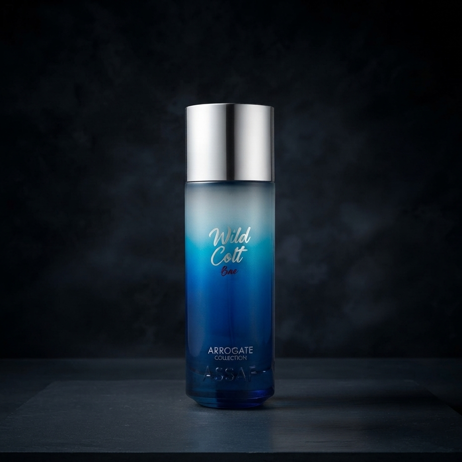 A tall cylindrical bottle of Wild Colt Blue cologne from the Associate Collection, featuring a blue gradient design and a shiny silver cap, set against a dark textured background. SHE GLOW 