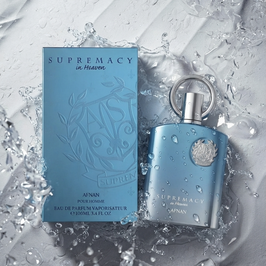 AFNAN Supremacy in Heaven Eau de Parfum for men, featuring a light blue rectangular box and a matching light blue cylindrical bottle with a silver cap, both decorated with water droplets, set against a dynamic water splash background.    SHE GLOW
