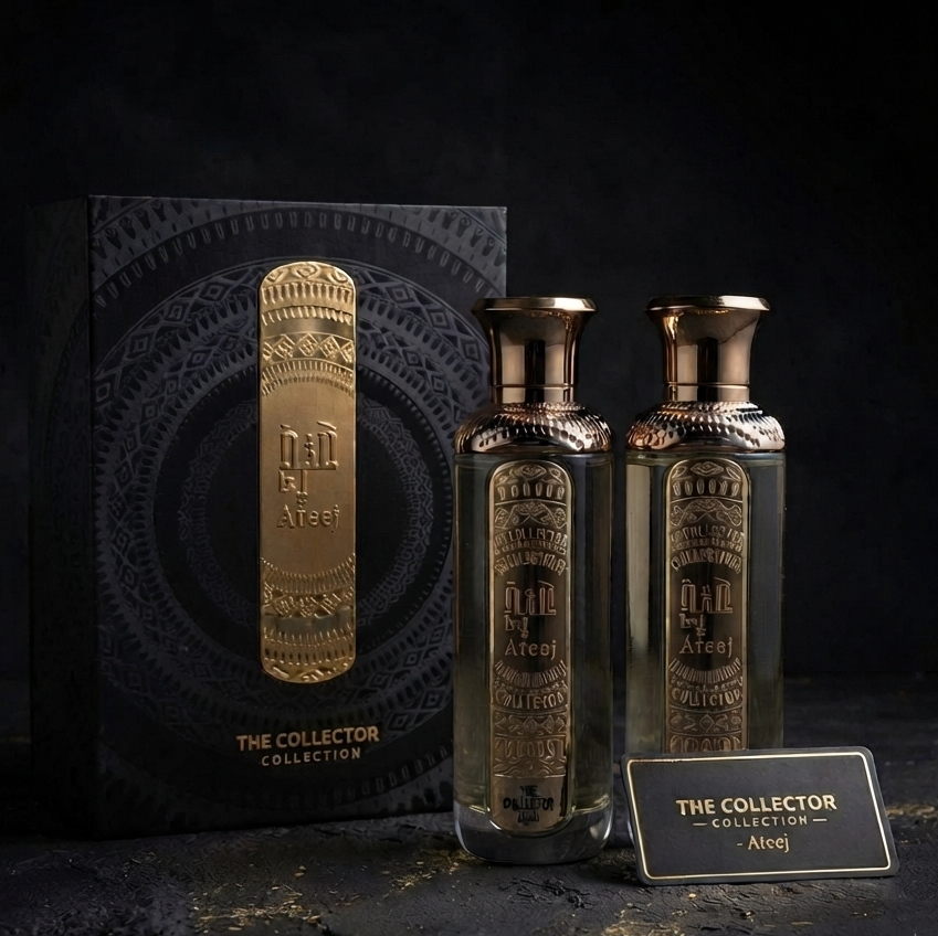 Two ornate glass bottles of Dar Al-Arefeyn 'The Collector' Arore perfume oil with gold caps, displayed next to their matching black patterned packaging box and a small gold label card on a dark textured surface.  
SHE GLOW ✨