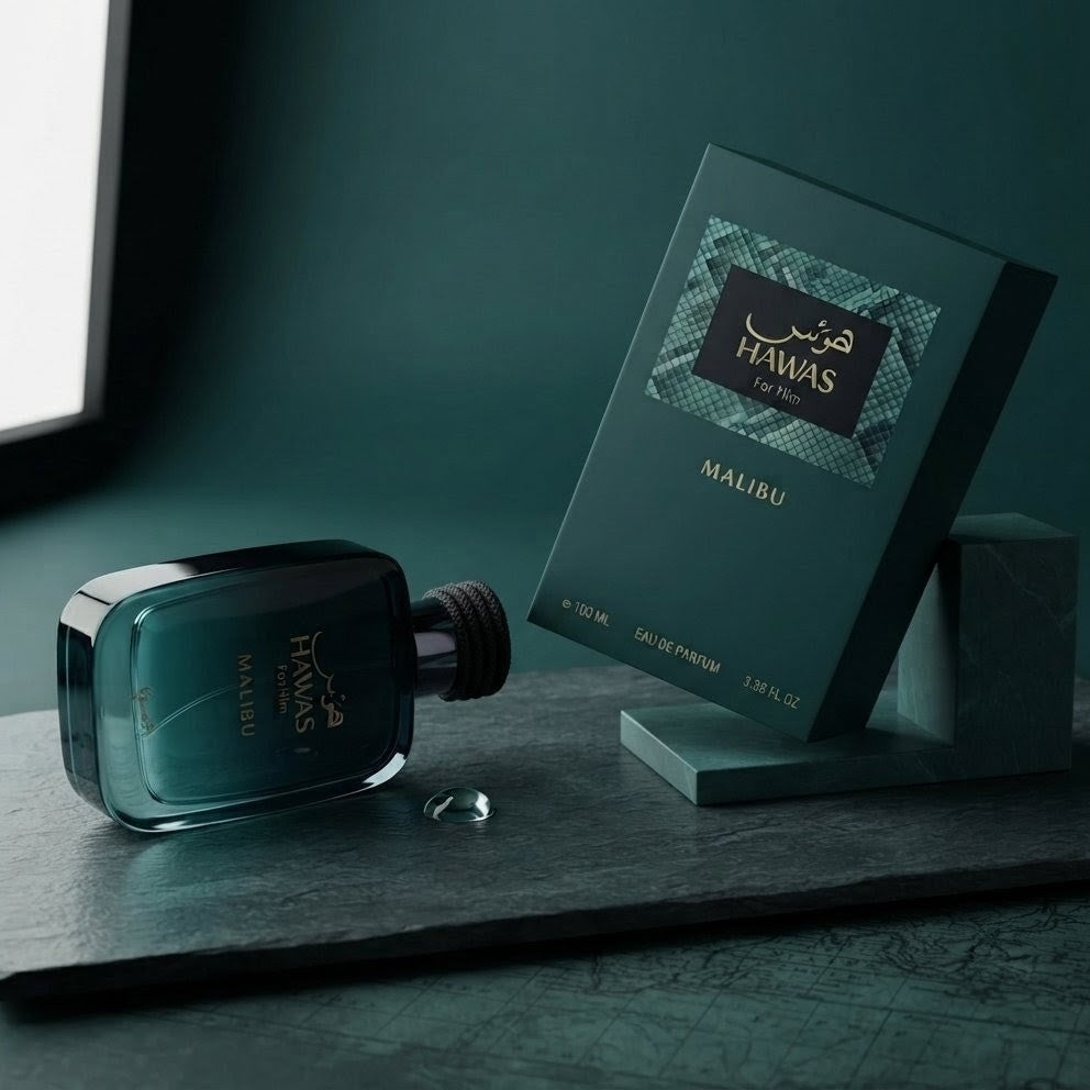 A dark teal glass perfume bottle and its matching retail box displayed on a dark stone surface against a deep teal background. The box shows the fragrance name MALIRU and the brand HAWAS.
SHE GLOW ✨