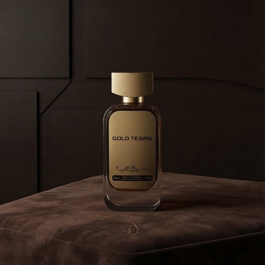 Gold Tears cologne bottle with a gold cap and gold label, set on a dark brown velvet surface against a dark wood-paneled
 SHE GLOW ✨