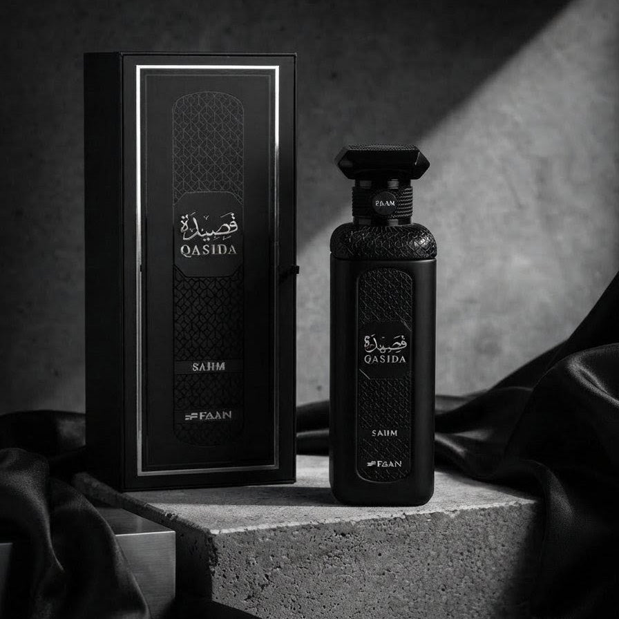 A black perfume bottle and its matching black box with silver trim, labeled Qasida Al-Rumeeh by Al-Fayan, displayed on a textured stone pedestal with draped black fabric against a dark studio background.      SHE GLOW ✨