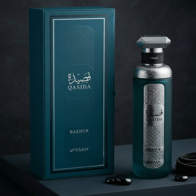 A teal and silver Qasida Bakhur fragrance bottle displayed next to its matching teal packaging box on a dark textured surface.
SHE GLOW ✨