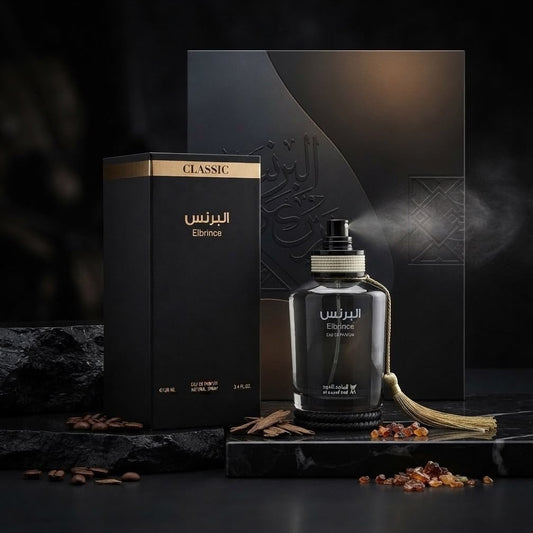 A dark glass perfume bottle labeled 'Elmoss' with Arabic text, shown next to its black packaging box with gold accents. The bottle is styled on a dark marble surface with coffee beans and spices, with a matching black presentation box and backdrop behind it. SHE GLOW ✨