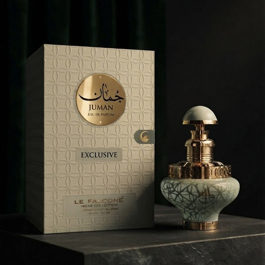 Le Falconé Juman Exclusive perfume bottle and its textured cream-colored packaging box, displayed on a dark stone surface against a dark background.SHE GLOW