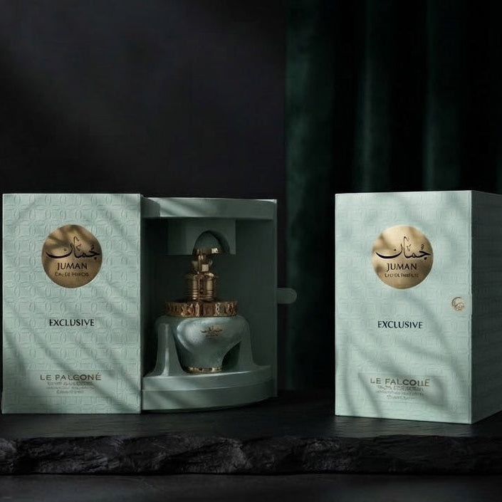A perfume bottle in a matching pale mint-green box sits beside a second closed box on a dark stone surface against a dark draped backdrop. The bottle has a gold-toned cap and the packaging features a circular gold emblem and the brand name 'Piquimé' visible on the front. SHE GLOW 
