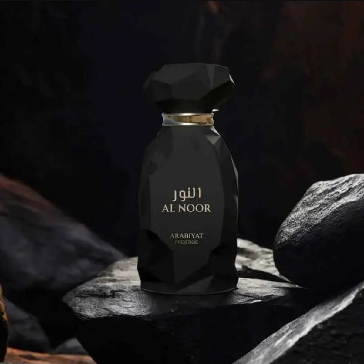A faceted black perfume bottle labeled 'AL NOOR ARABIYAT PRESTIGE' in gold lettering, set on dark rocks against a dark, moody background. SHE GLOW