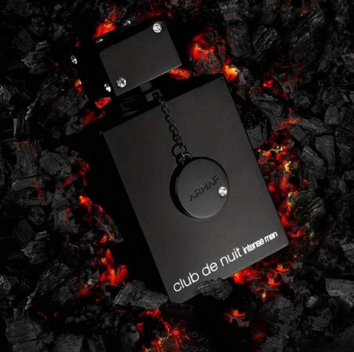 Black perfume bottle labeled 'club de nuit intense man' on a fiery background SHE GLOW